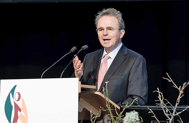 Dr. Jens Kreuter, Geschäftsführer von Engagement Global, hält die Begrüßungsworte an die Teilnehmenden. Er steht hinter einem Rednerpult mit Mikrofon und gestikuliert.
